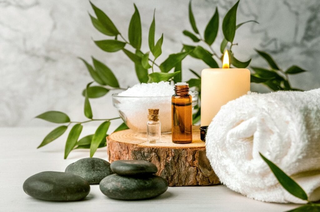 beauty treatment items for spa procedures on white wooden table. massage stones, essential oils and sea salt. copy space